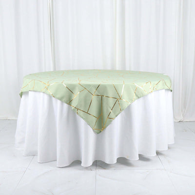 Green tablecloth with gold geometric pattern draped over a white table.