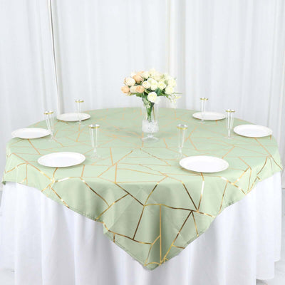 Green geometric tablecloth on a round table with plates and a flower vase.