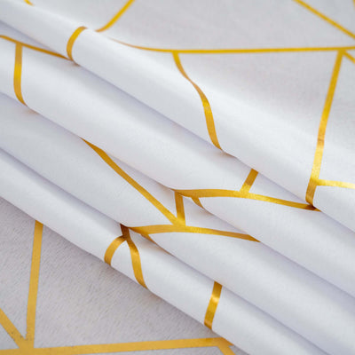 White fabric with gold geometric patterns folded neatly.