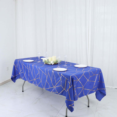 Blue geometric tablecloth on a dining table with plates and floral centerpiece.