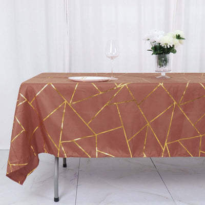 Geometric gold-accented tablecloth on a dining table with glassware and flowers.
