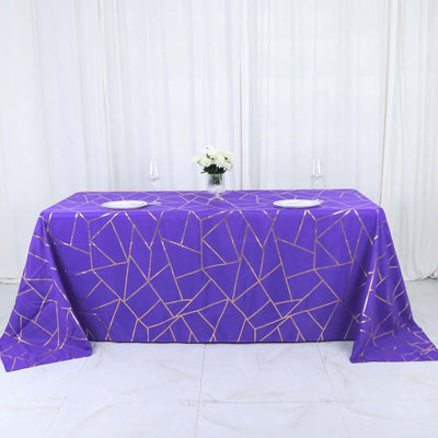 Purple geometric tablecloth with gold accents on a table setting.