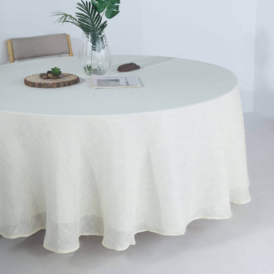 Round light beige tablecloth draped over a table with decor items.