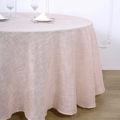 Pink round tablecloth on a dining table with wine glasses and napkins.