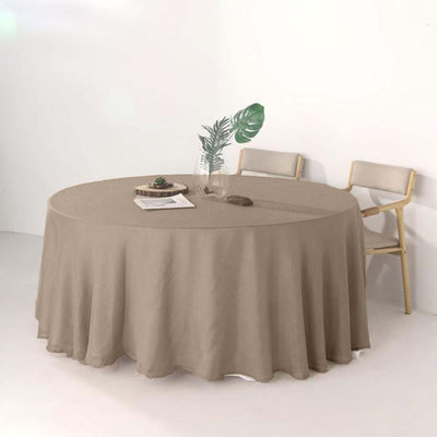 Round beige tablecloth draped over a round table with chairs and a plant.