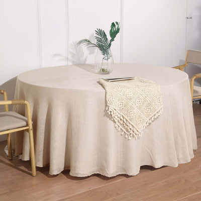 Round beige tablecloth on a dining table with a decorative lace runner.