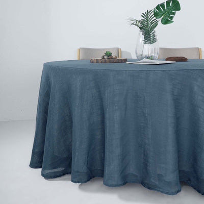Blue linen tablecloth draped over a round table with decor elements