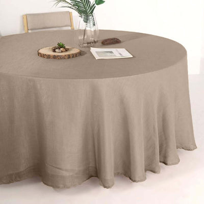 Round beige tablecloth draping over a table with natural decor elements.