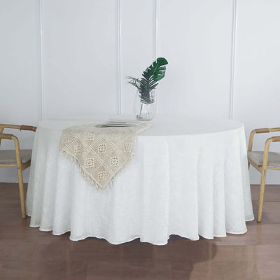 White tablecloth draped elegantly over a round table with a vase and plant