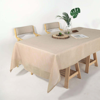 Elegant beige tablecloth draped on a wooden table with chairs and decor.