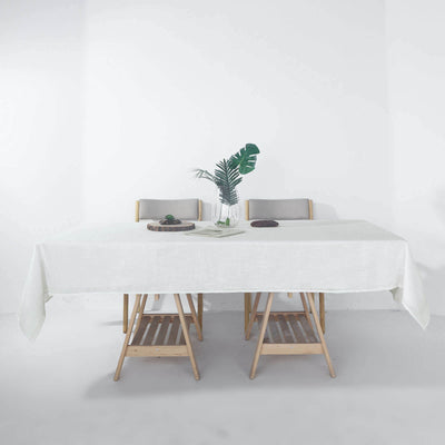 Modern dining table with minimalist decor and greenery in a bright setting.