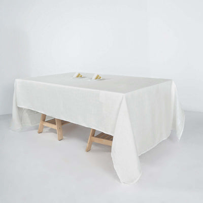 White tablecloth draped over a wooden table on a plain backdrop.