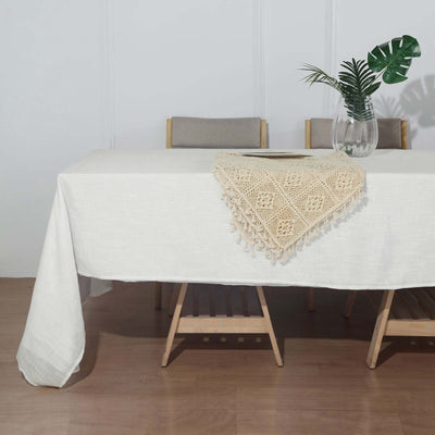White tablecloth with decorative beige crochet trim on a dining table.