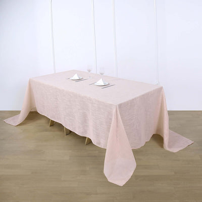 Pink tablecloth draped over a dining table with plates and glasses.