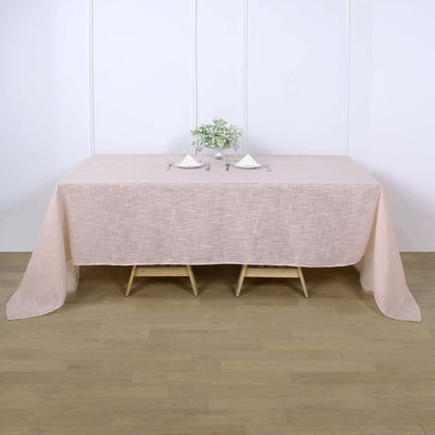 Pink textured tablecloth draped over a wooden table with decorative accents.