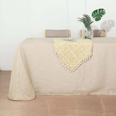 Beige tablecloth with decorative crochet overlay on a wooden table.