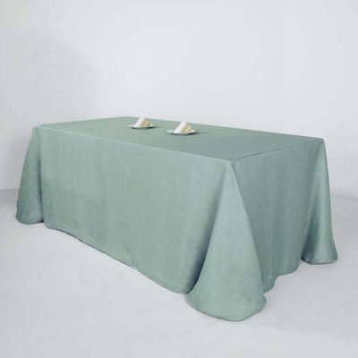 Green tablecloth draped over a rectangular table with two plates on top.