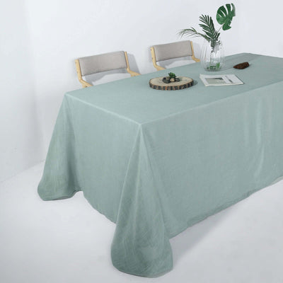 Mint green tablecloth draped over a table with chairs and decor.