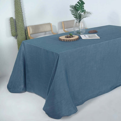 Blue linen tablecloth draped over a table with a plant and decor elements.