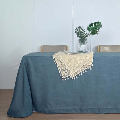 Table with blue linen tablecloth and decorative lace overlay.