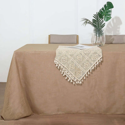 Beige tablecloth with crochet lace trim and decorative plant in a vase.
