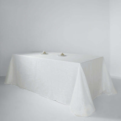 White tablecloth draped over a table with folded napkins on a plain background