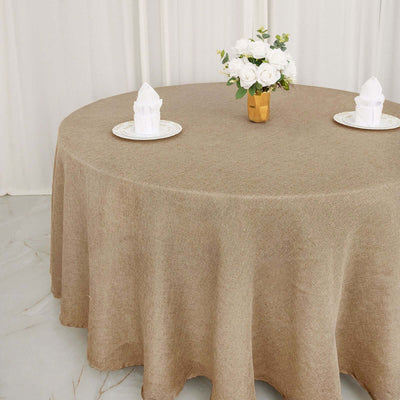 Round brown tablecloth on a dining table with a flower vase and napkins.