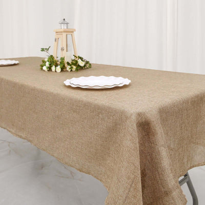 Burlap tablecloth draped over a table with decorative plates and flowers.
