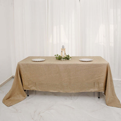 Decorative table with a beige tablecloth, plates, and a lantern centerpiece.