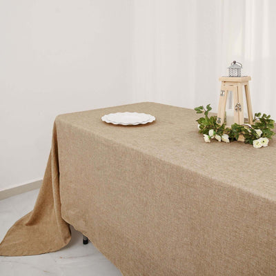 Brown linen tablecloth draped over a table with a decorative stand and plate.