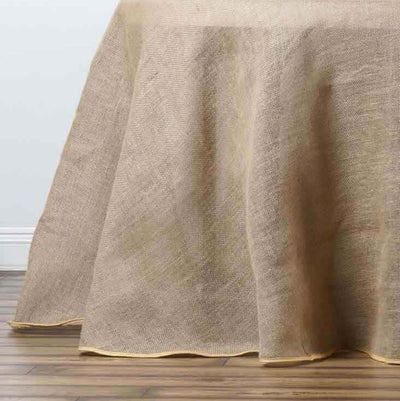 Natural burlap tablecloth with yellow trim on a wooden surface.