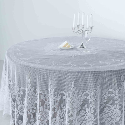 Elegant round lace tablecloth on a dining table with candles and dessert.