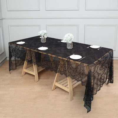 Black lace tablecloth draped over a wooden table with plates and vases.