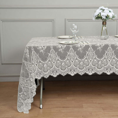 Lace tablecloth elegantly draped over a table with plates and glassware.