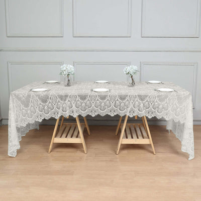 Lace tablecloth draped over a wooden table with flower arrangements.