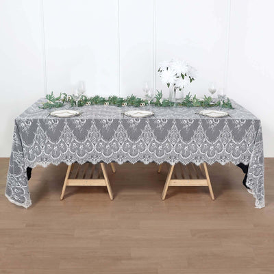 Elegant gray lace tablecloth set on a wooden table with floral decor.