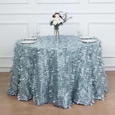Round table covered with a light blue leaf-patterned tablecloth, set for dining.