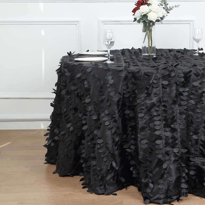 Black tablecloth with leaf design draped over a round table, elegantly styled.