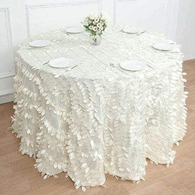 White tablecloth with leaf embellishments draping over a round table.