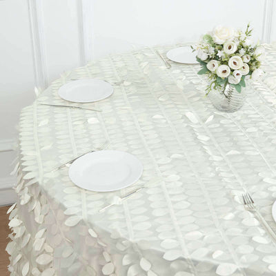 Elegant round table set with a decorative leaf-pattern tablecloth and floral centerpiece.