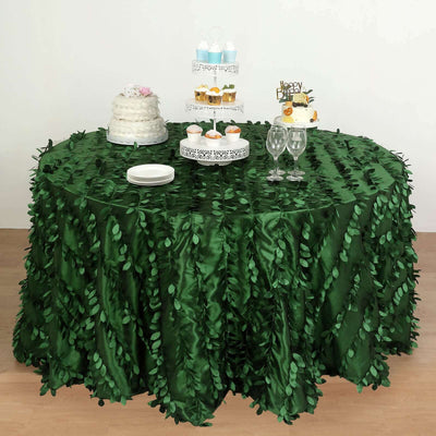Green leaf tablecloth draped over a round table with desserts and plates.