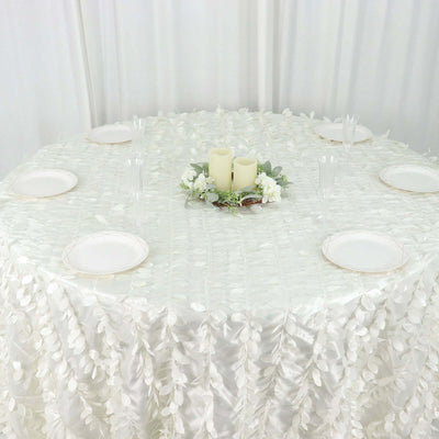 Elegant white table setting with candles and floral centerpiece on a textured tablecloth.