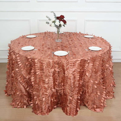 Round table with a rose gold leaf-patterned tablecloth and white plates.