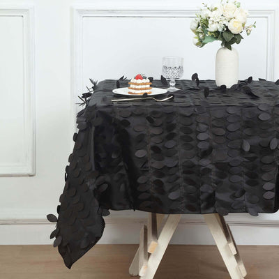 Black textured tablecloth draped over a table with a cake and flowers.