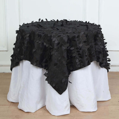 Black leaf-patterned tablecloth draped over a white table.