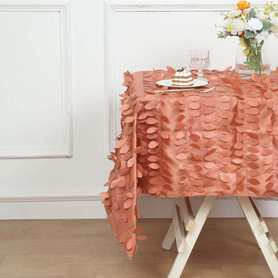 Rustic orange tablecloth with leaf appliqués on a wooden table setting.