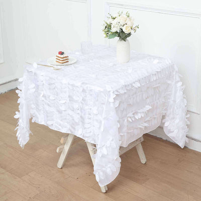 White floral tablecloth draped over a table with a vase and dessert.