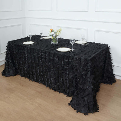 Black ruffled tablecloth on a dining table set with plates and glasses.
