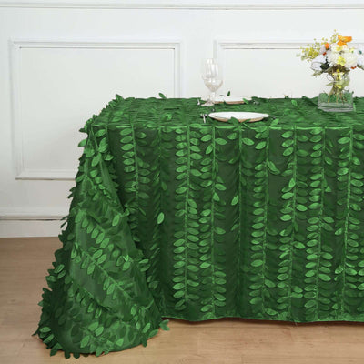 Green leaf-patterned tablecloth on a dining table with glassware and flowers.