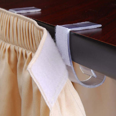 Curtain clip holding fabric on a table edge for secure placement.